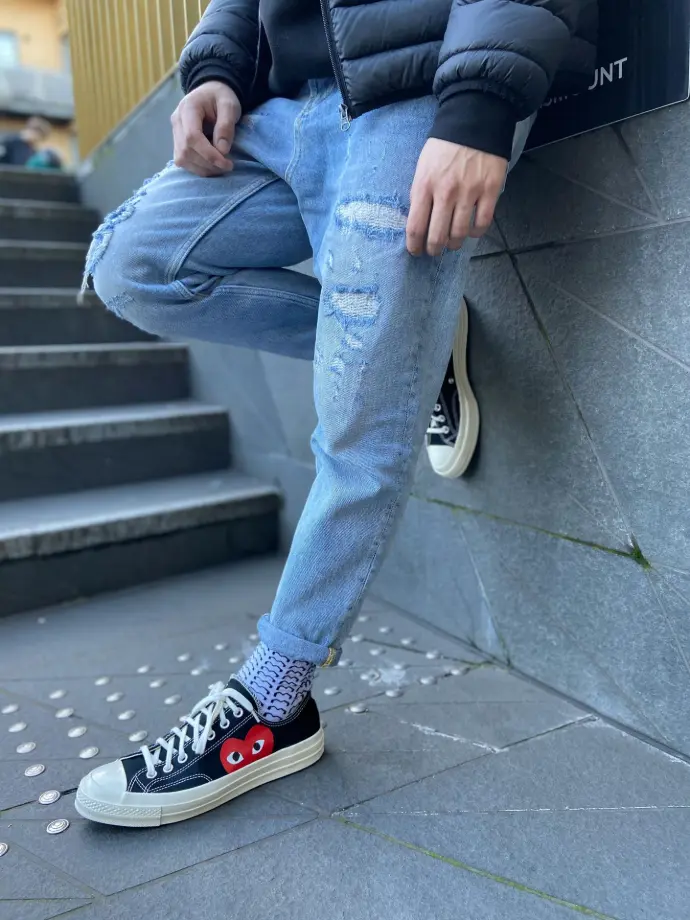 person in blue denim jeans and black and white converse all star high top sneakers
