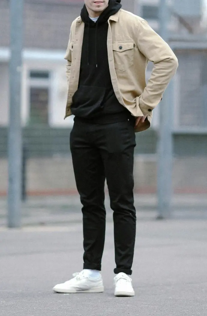 man wearing brown jacket and black pants standing near basketball ring
